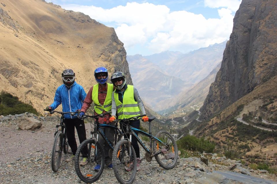 Tres ciclistas con casco en un camino de montaña del Valle Sagrado