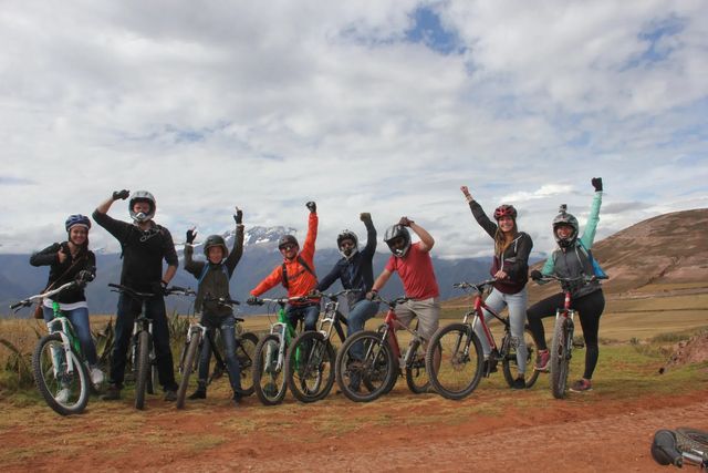 Grupo de ciclistas celebrando con sus bicicletas frente a las montañas