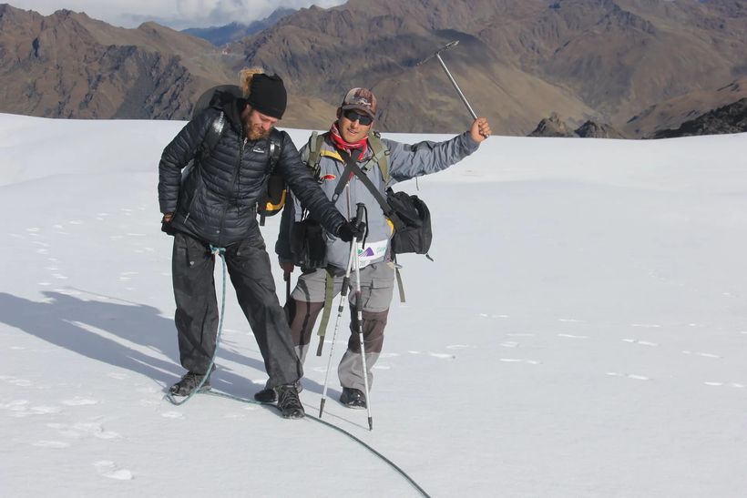 Guide and traveller walking on the snow of an Andean glacier