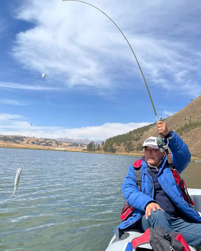 Pescador sacando un pejerrey en una laguna andina