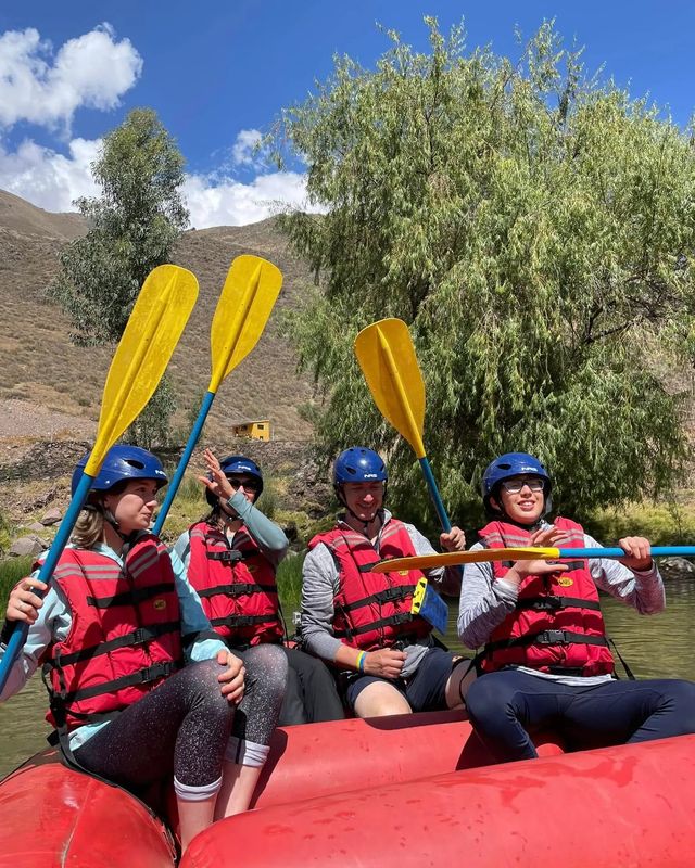 Cuatro viajeros con casco, chaleco y remos listos para el rafting