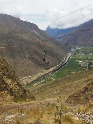 Zipline cable crossing the valley above farm fields